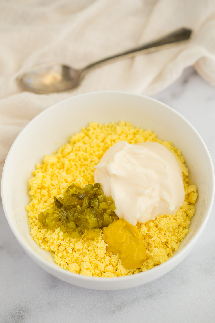 A white bowl filled with crumbled egg yolks, mayonnaise, mustard, and relish.