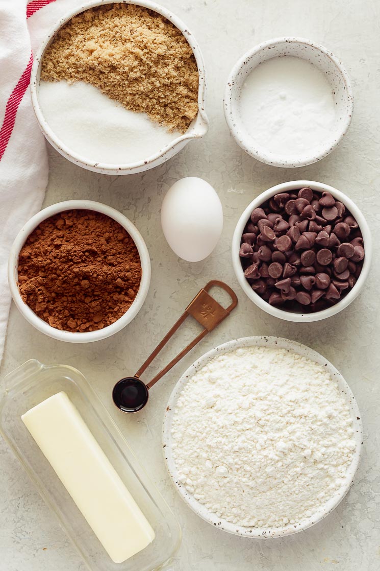 The ingredients needed for double chocolate chip cookies on a gray surface.