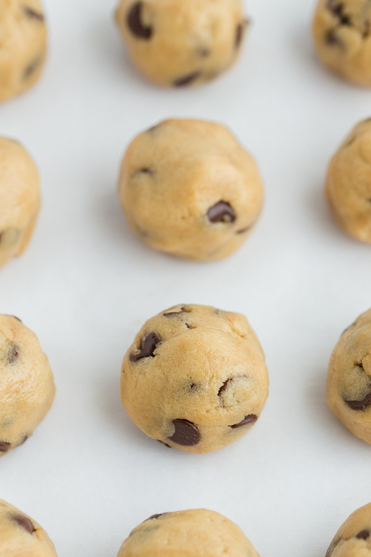 Edible cookie dough rolled into balls on a piece of parchment paper.