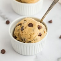 A close-up picture of edible cookie dough inside of a white ramekin.