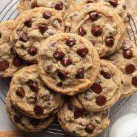 A pile of chocolate chip cookies in a round wire cooling rack.