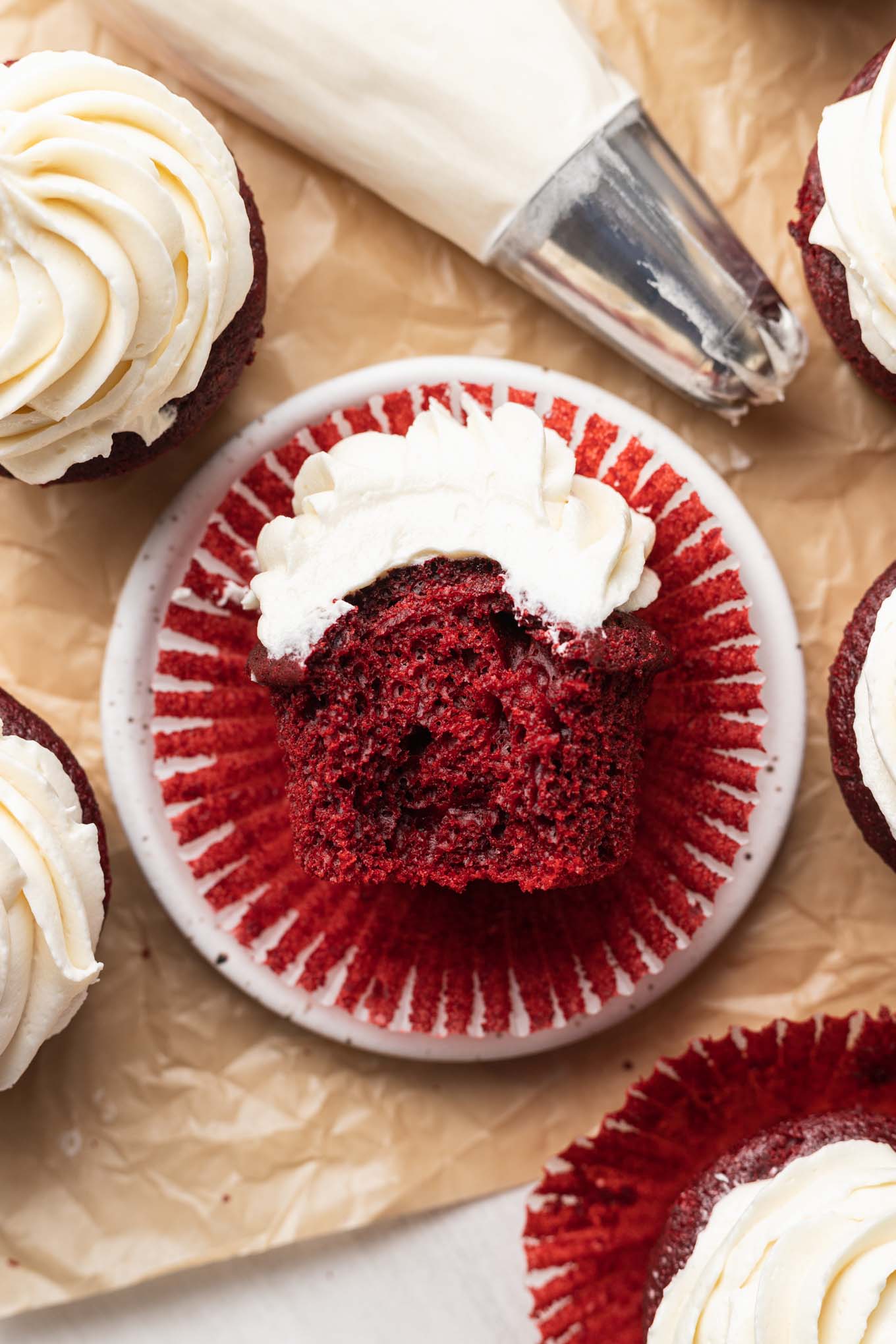 An overhead view of a frosted red velvet cupcake with a bite missing, turned on its side. 