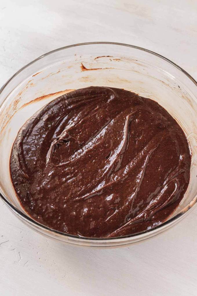 A glass mixing bowl full of chocolate cake batter.