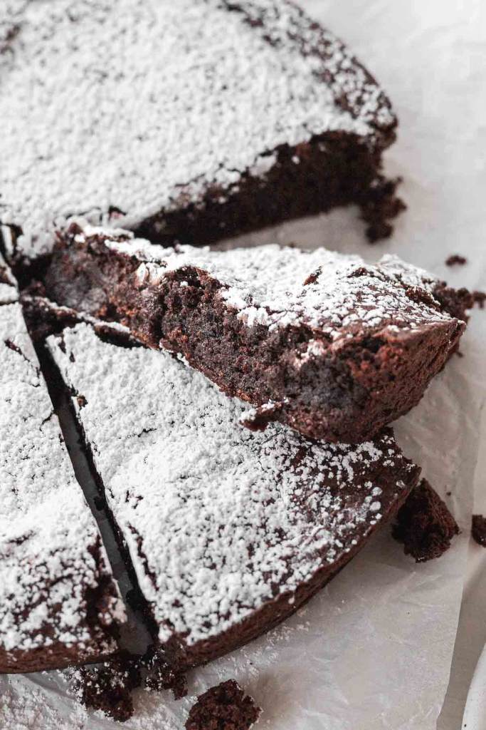 A close up view of a slice of flourless chocolate cake that's been turned on its side. 