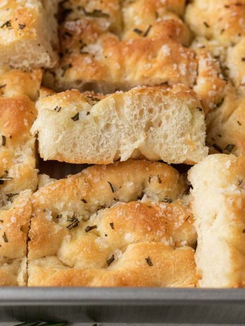 Several slices of focaccia bread in a metal baking pan.