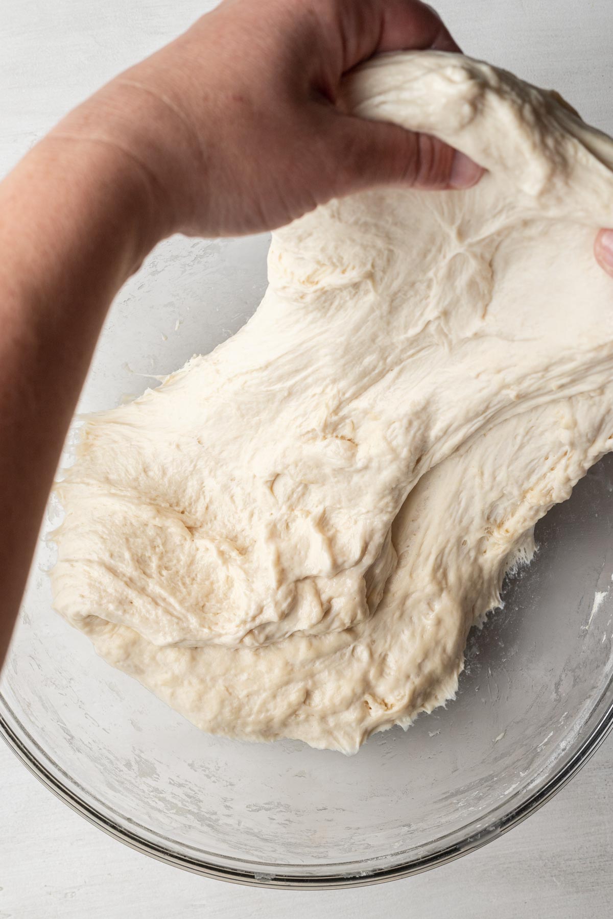 A process shot showing how to stretch and fold focaccia dough.