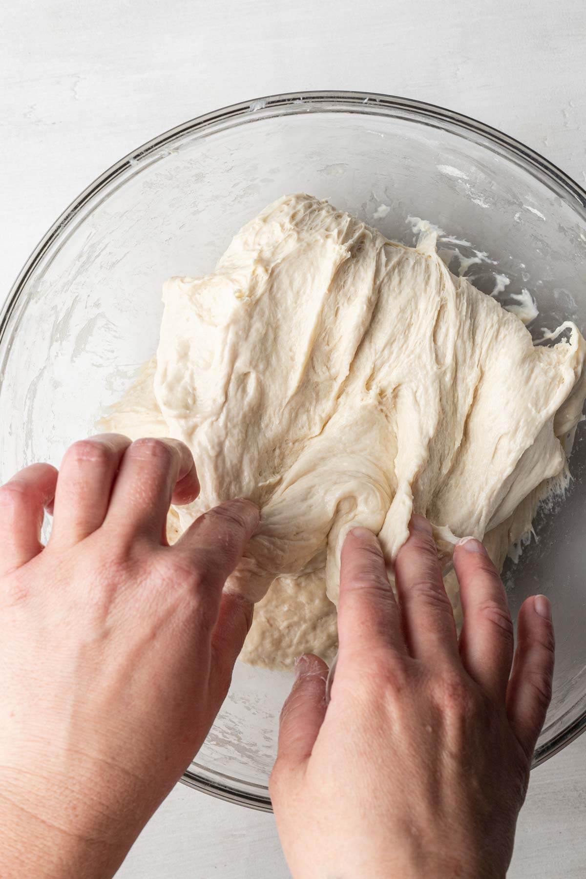 A process shot showing how to stretch and fold focaccia dough.