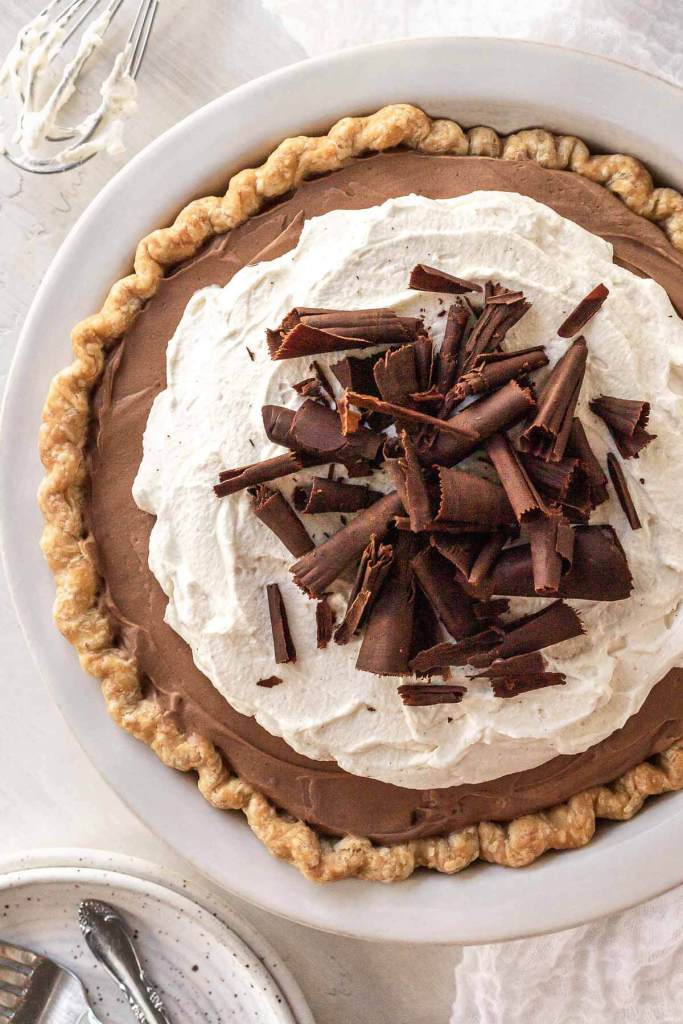 An overhead view of a French silk pie garnished with chocolate shavings in a white pie plate. 