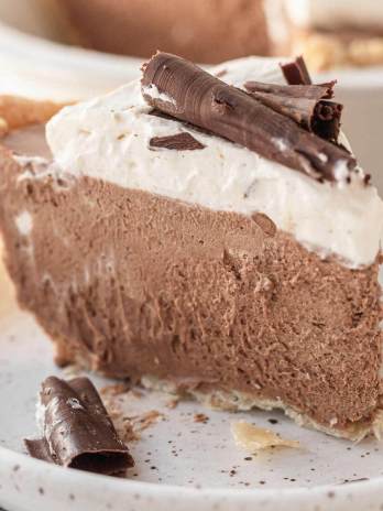 A slice of French silk pie topped with homemade whipped cream and chocolate curls.