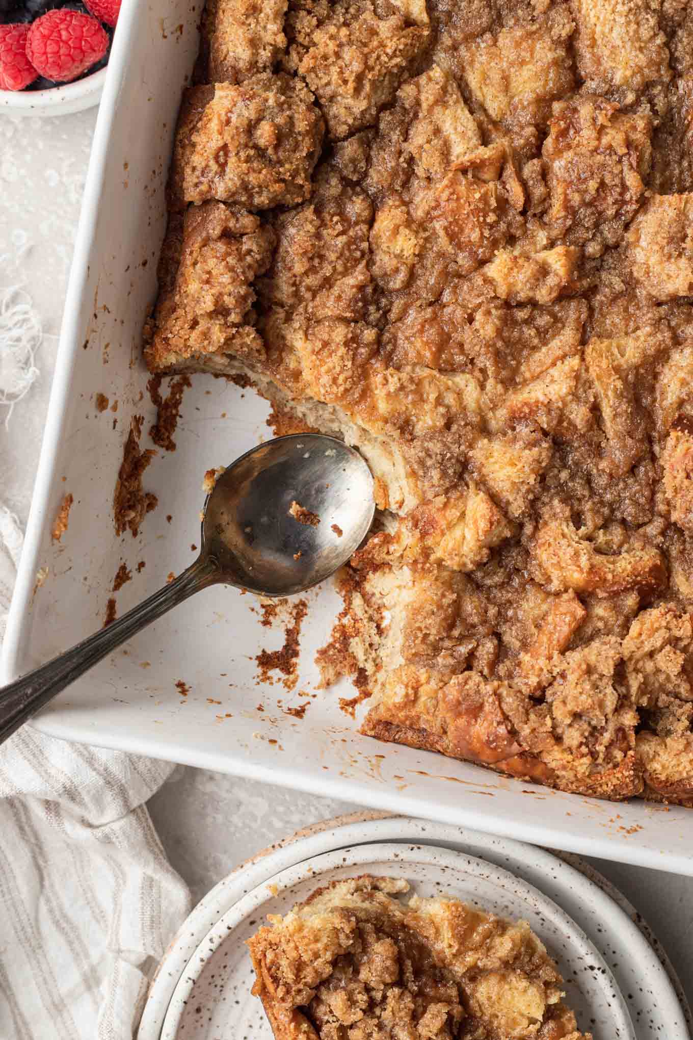 An overhead view of a casserole dish of baked french toast, with a serving missing. 