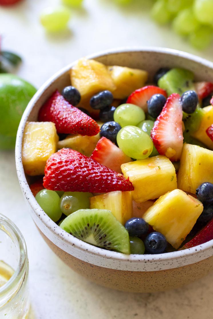 A rustic clay bowl filled with fresh fruit salad.