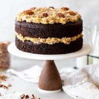 A layered German Chocolate Cake on top of a marble cake stand.