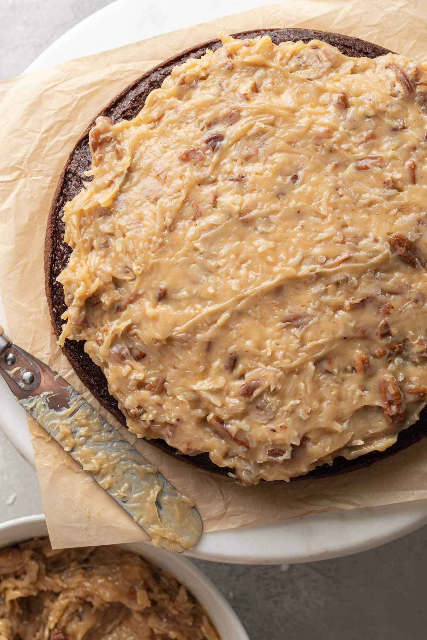 An overhead view of a German chocolate cake being frosted. 