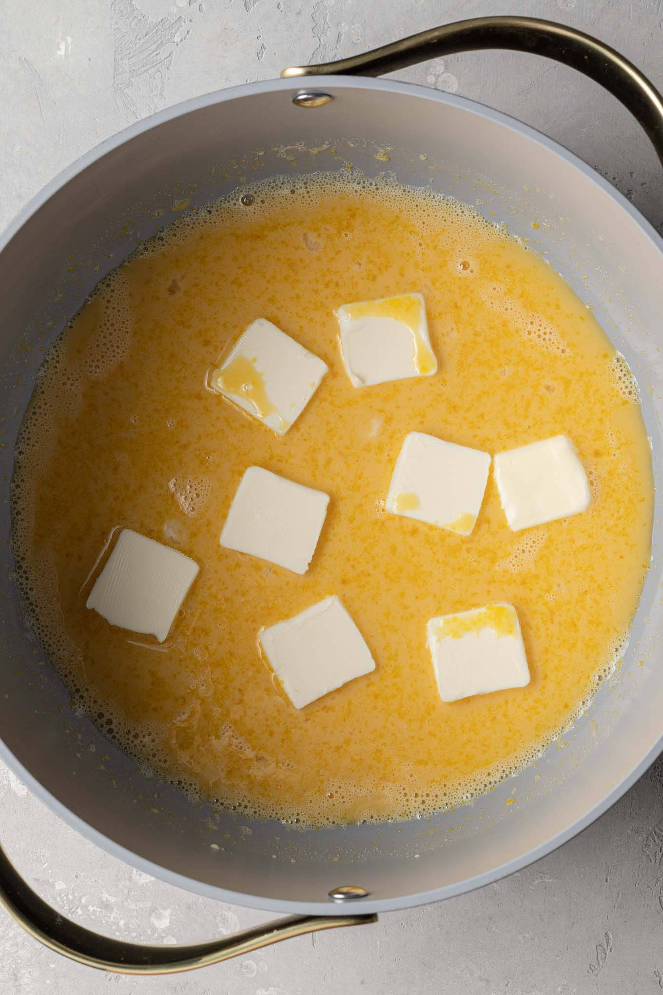 An overhead view of an egg yolk and butter mixture in a saucepan. 