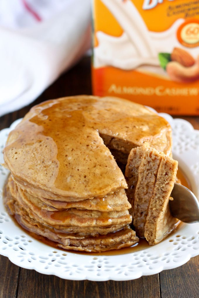 Stack of gingerbread pancakes on a white plate. A bite has been cut out. 