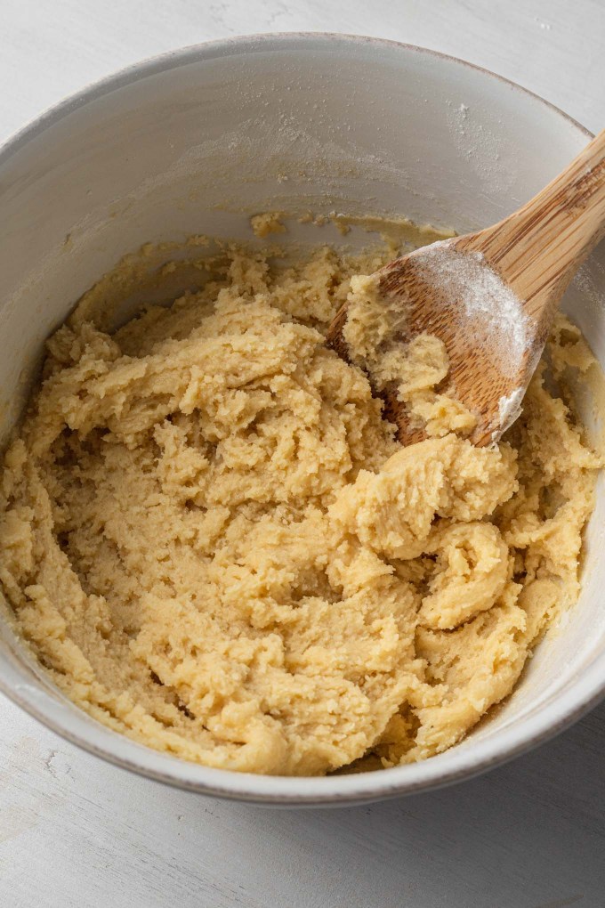 Thick cake batter in a white mixing bowl with a wooden spoon.