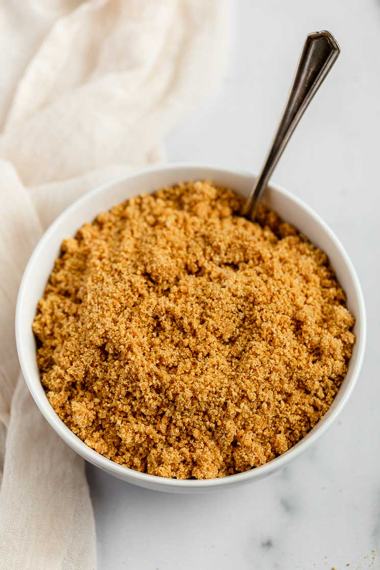 The mixture for a graham cracker crust mixed up in a white bowl.