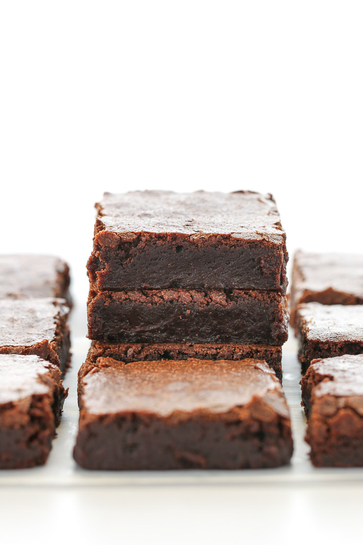 A stack of sliced brownies on top of a piece of parchment paper with other brownies around it.