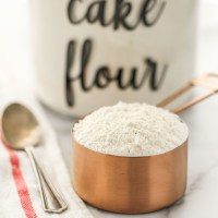 A close-up picture of a copper measuring cup filled with cake flour.