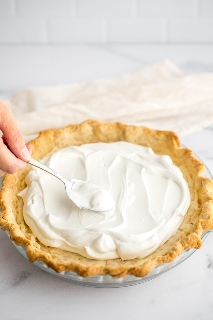 A close-up of whipped cream being added to the top of the pie.