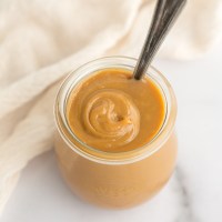 A close-up image of dulce de leche in a small glass jar.