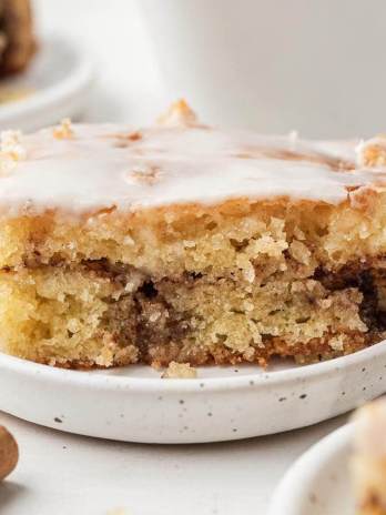 A slice of honey bun cake on a white speckled plate.