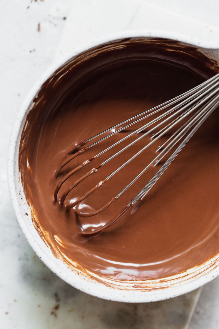 A white mixing bowl filled with chocolate ganache that has been mixed up.