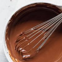 A white mixing bowl filled with chocolate ganache that has been mixed up.