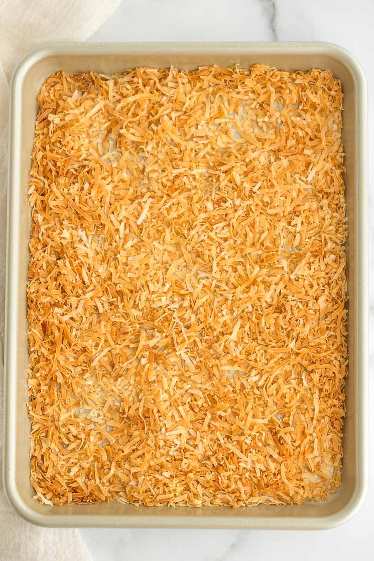 A batch of toasted coconut spread out onto a baking sheet. 