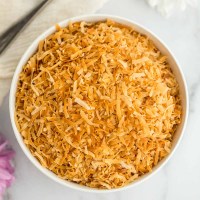 A white bowl filled with toasted coconut.