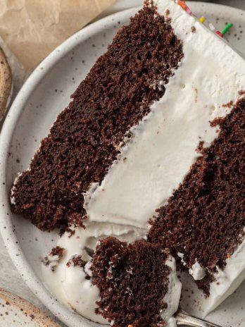 A slice of ice cream cake on a white plate. A fork with a piece of the cake is resting on the side.