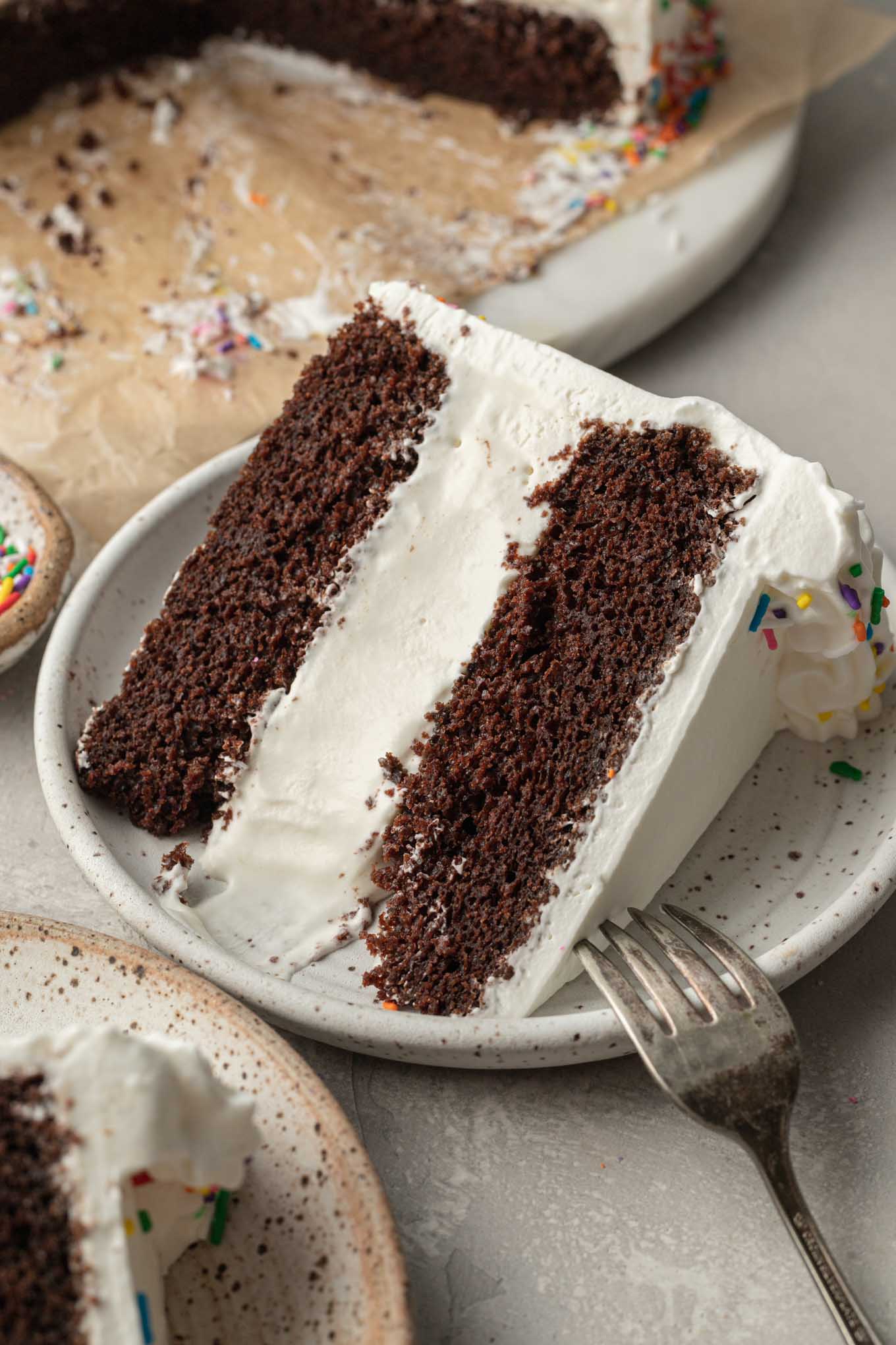 A slice of ice cream cake on a white plate with a fork next to it.