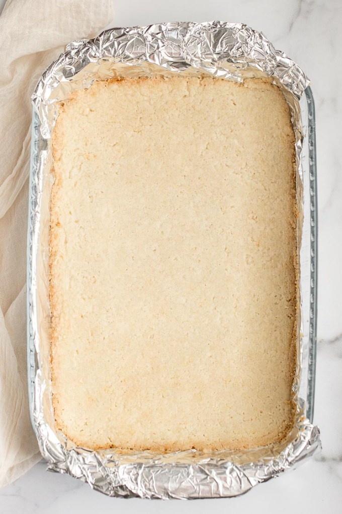 The baked shortbread crust in a pan lined with aluminum foil.