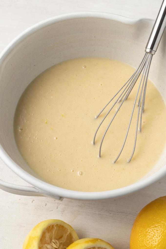 Lemon quick bread batter in a large mixing bowl, with a whisk resting inside.