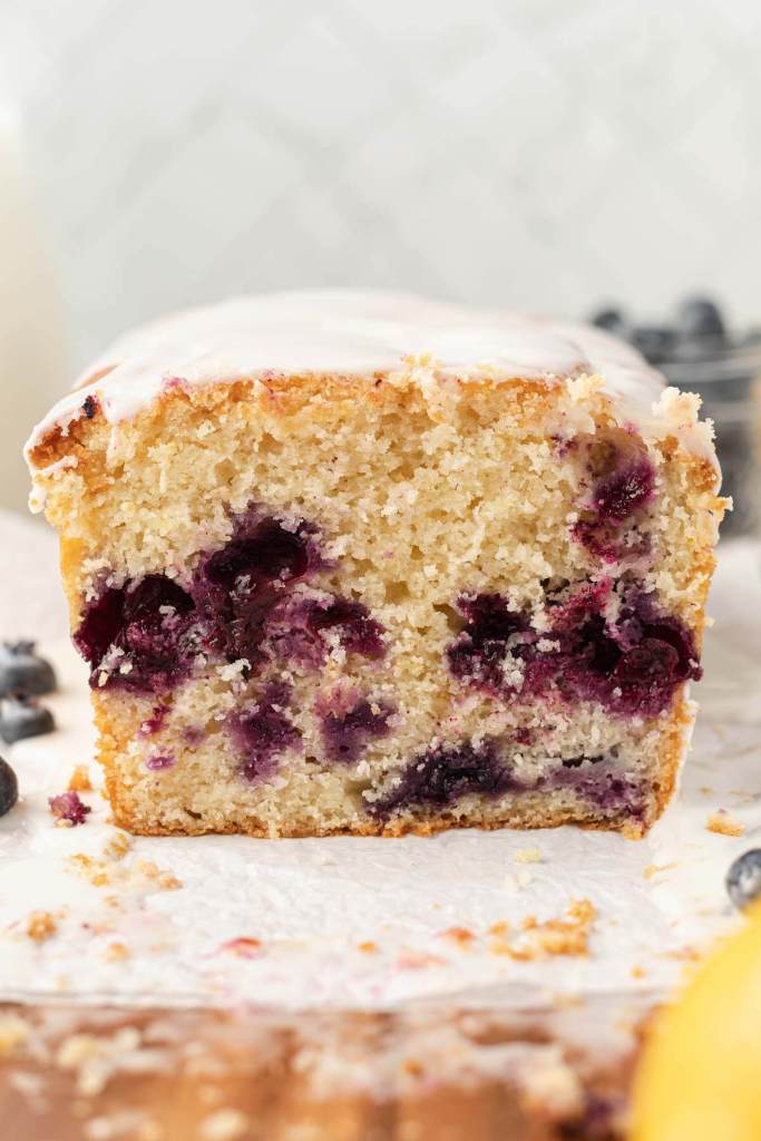 A front view of a loaf of lemon blueberry bread, sliced to show the interior. 