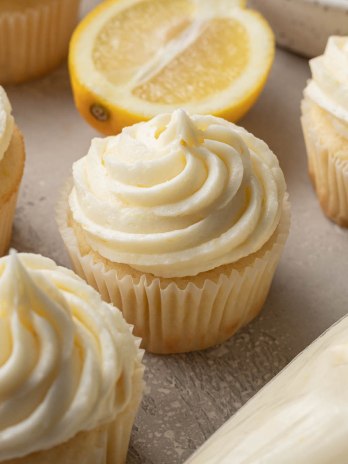 Several lemon cupcakes topped with lemon buttercream frosting.