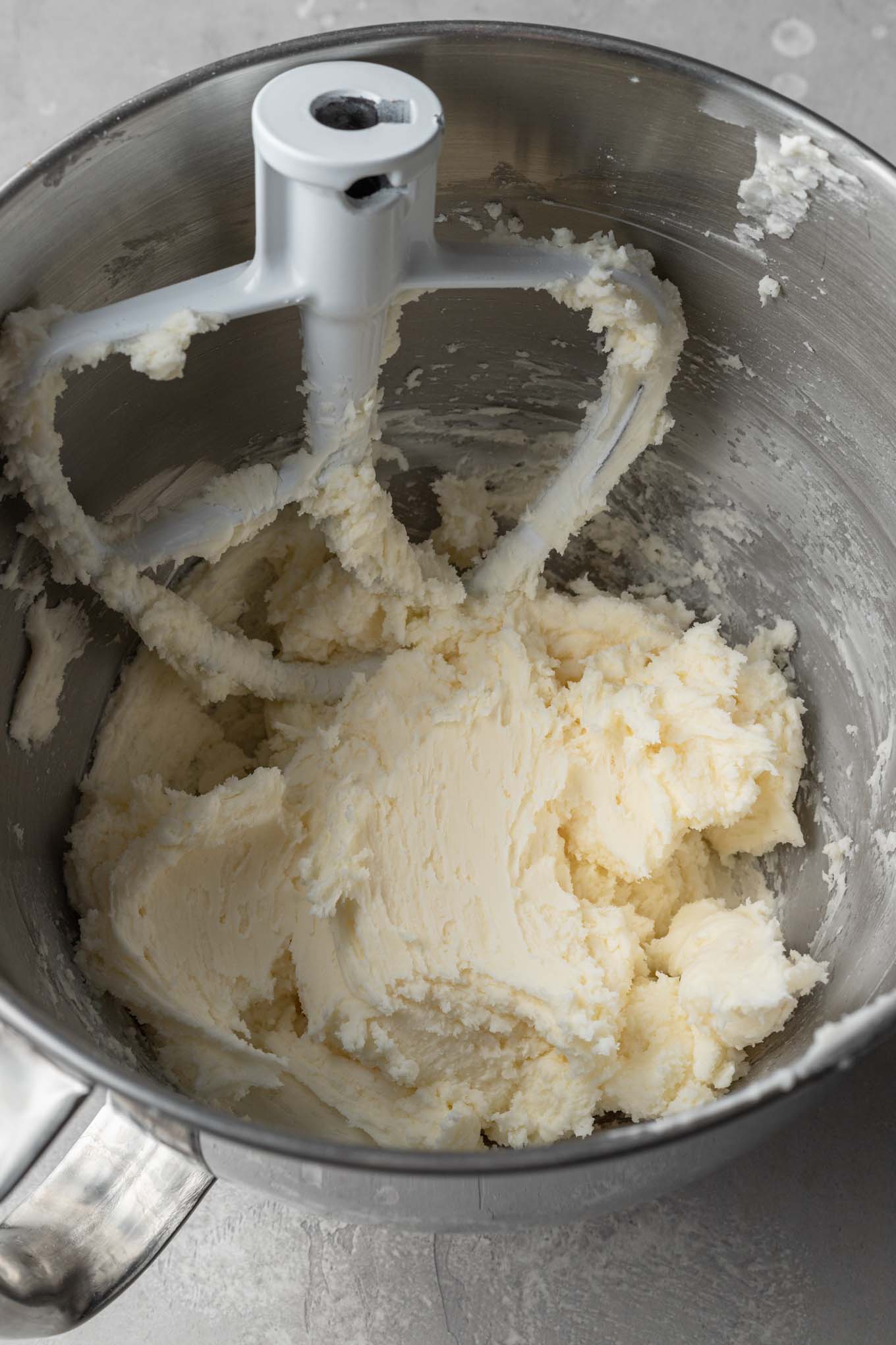 An overhead view of creamed butter and sugar in a mixing bowl. 