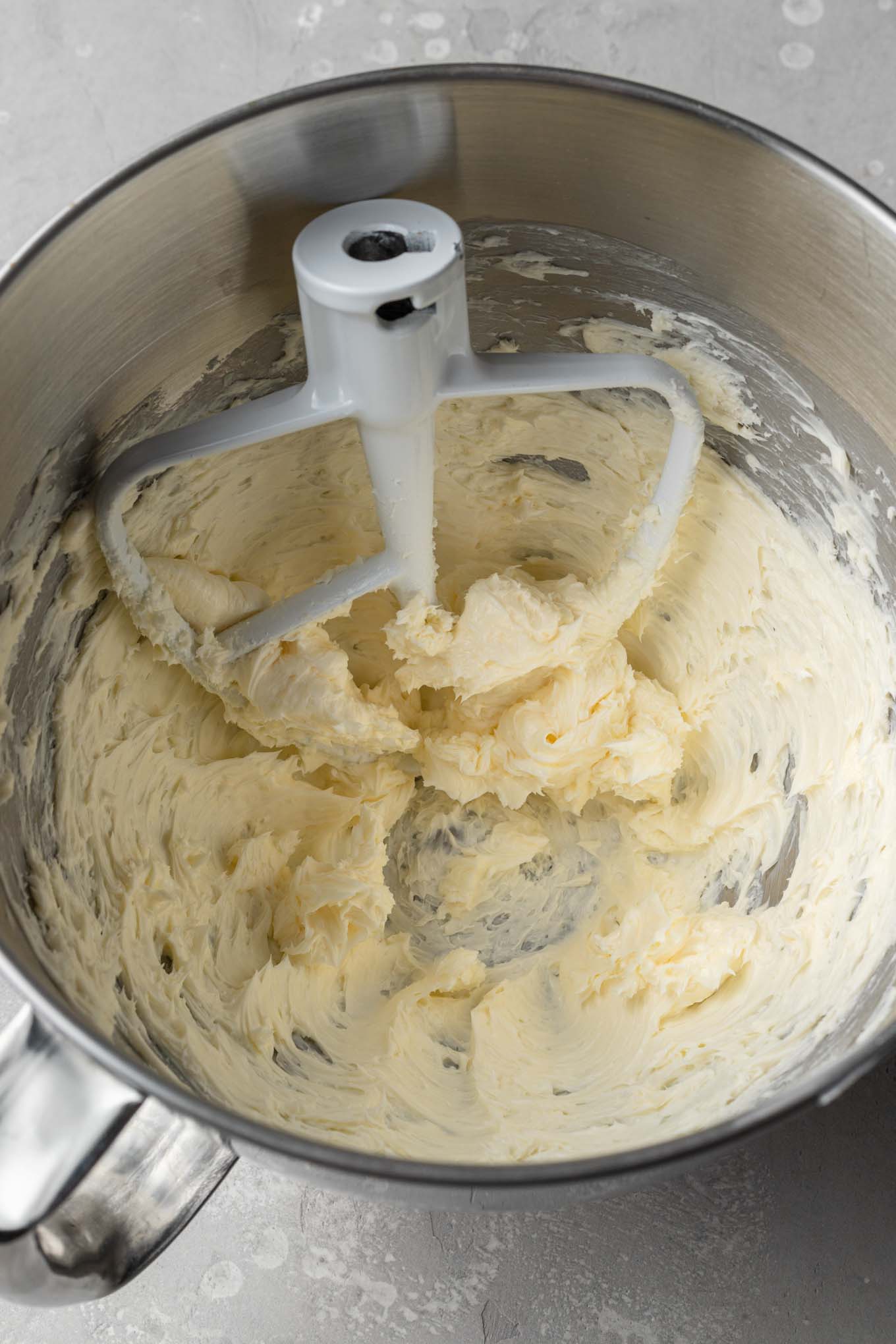 An overhead view of creamed butter in a mixing bowl. 