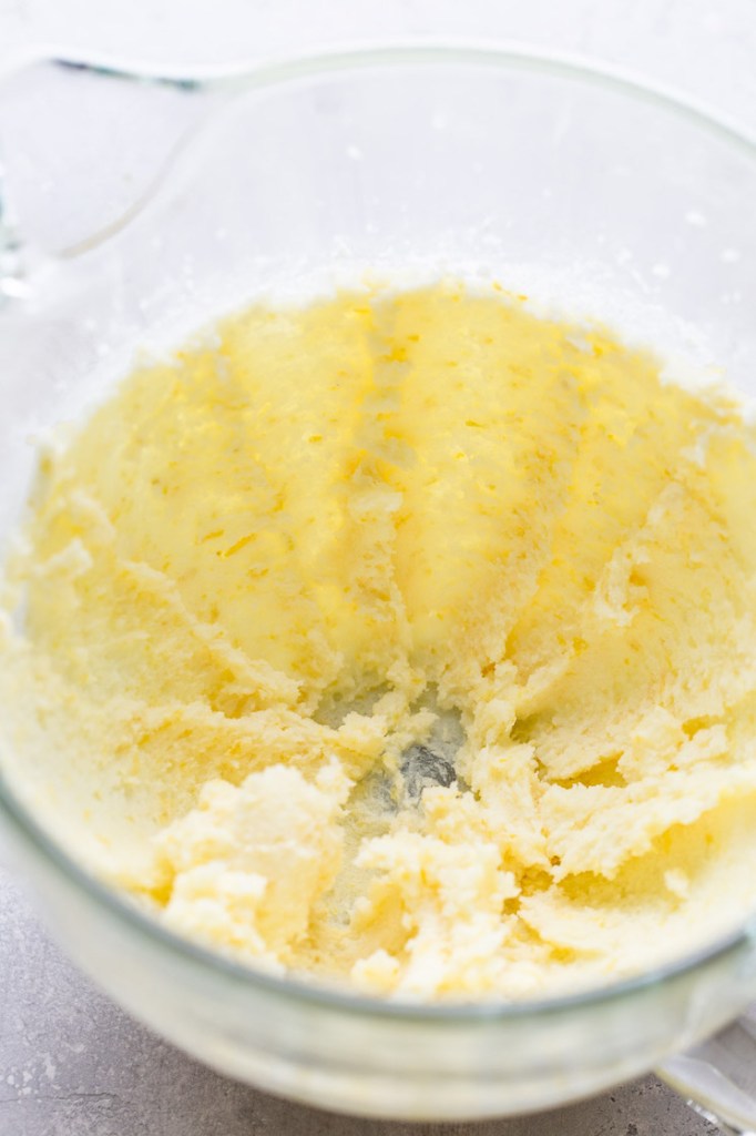 A glass mixing bowl with creamed butter and sugar. 