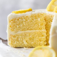 A side view of a slice of lemon cake being removed from a cake stand.
