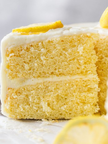 A side view of a slice of lemon cake being removed from a cake stand.