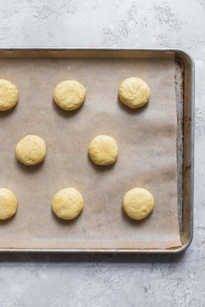 A cookie sheet lined with parchment paper holding balls of cookie dough ready to be baked.