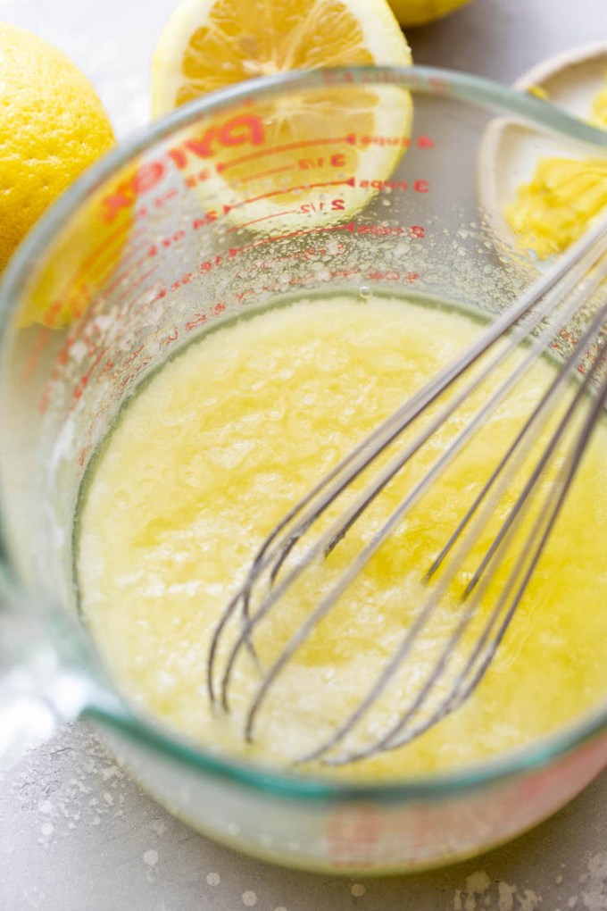 Butter and sugar being mixed together in a glass measuring cup.