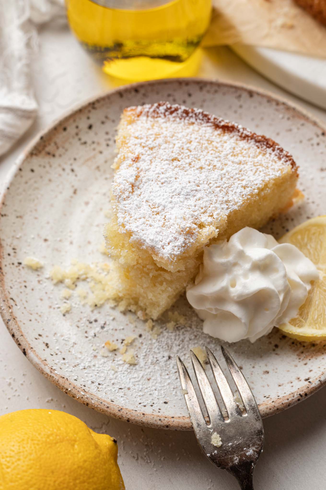 A slice of olive oil lemon cake with a bite missing. 