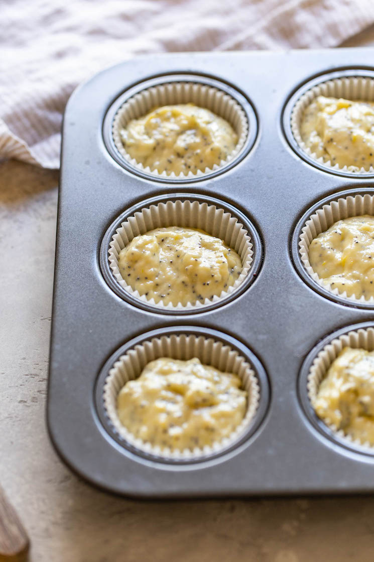 A muffin pan holding batter in muffin liners.