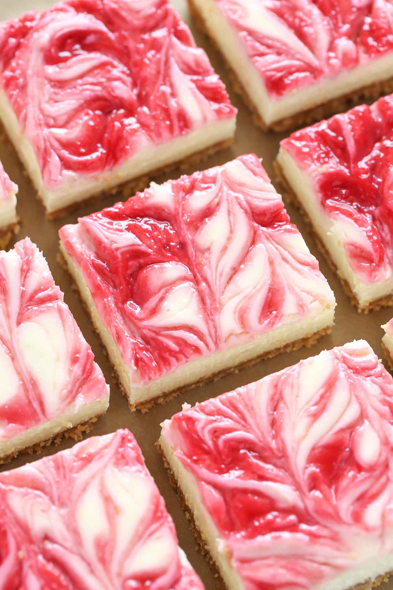 Overhead view of lemon raspberry cheesecake lined up in rows. 