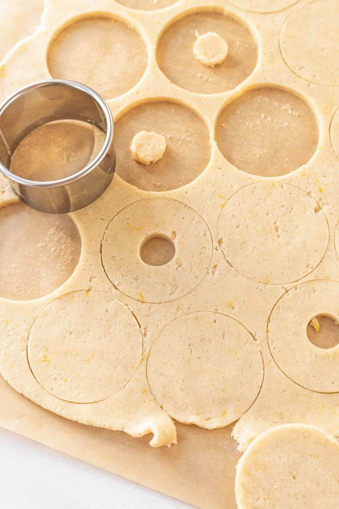 Rolled out cookie dough with circles being cut out of it.