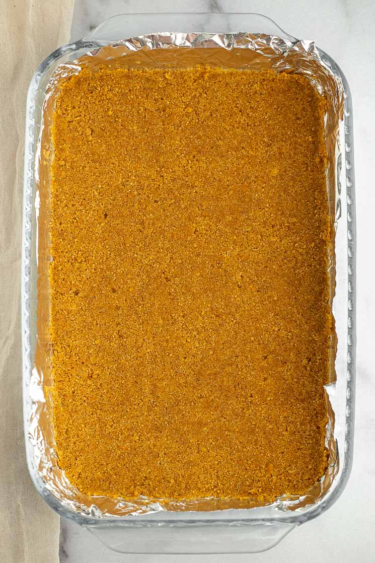 A graham cracker crust in a 9x13 pan lined with aluminum foil.