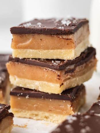 A stack of three millionaire shortbread bars topped with sea salt.