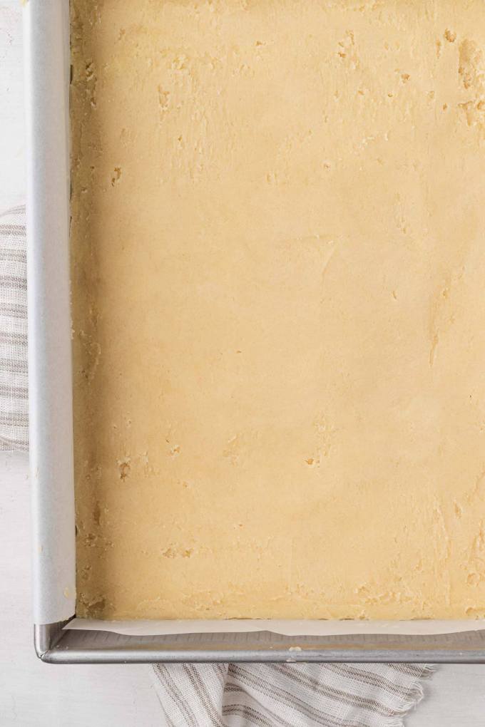 An overhead view of shortbread dough pressed into a baking pan.